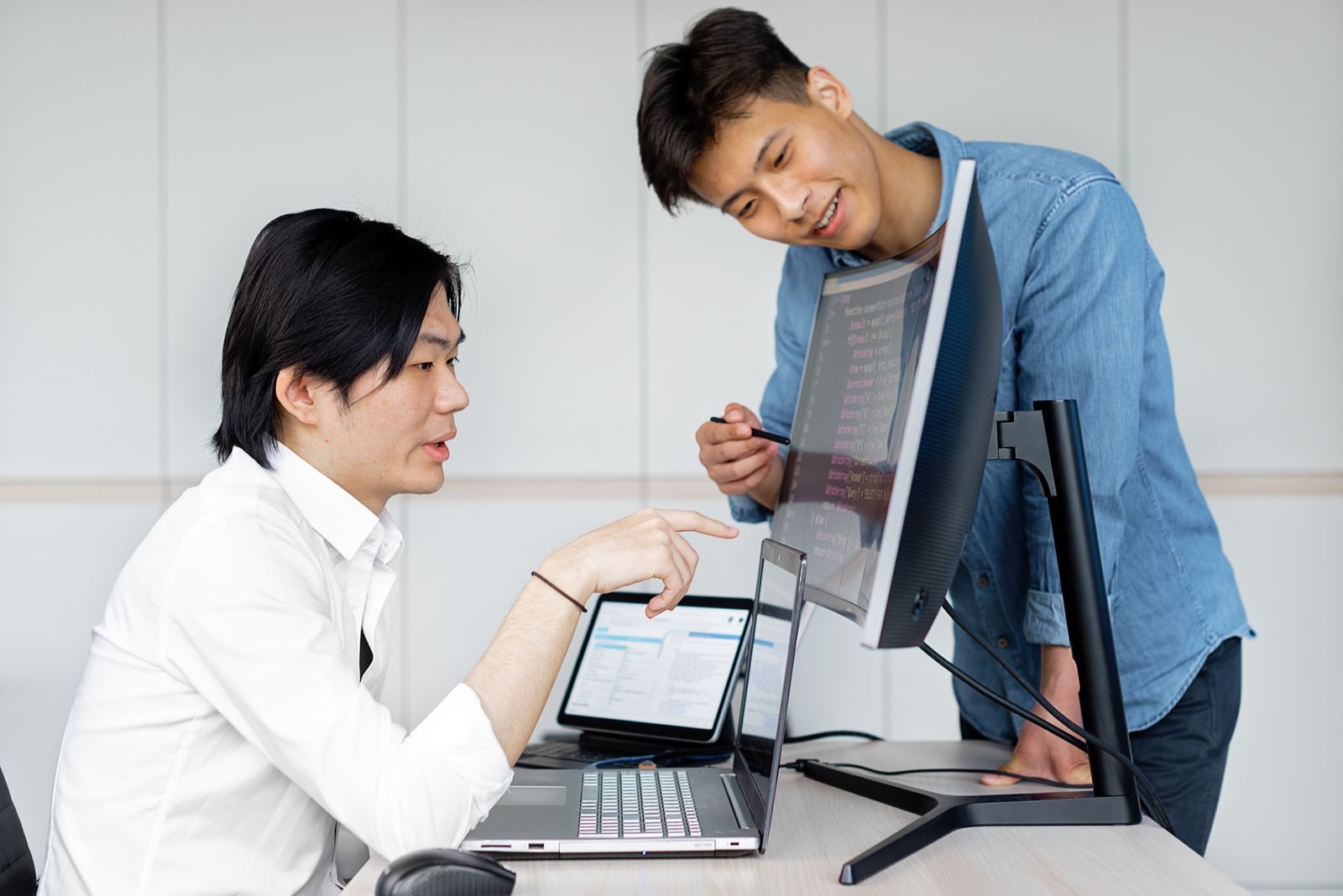 画面を見ながら話し合うエンジニア